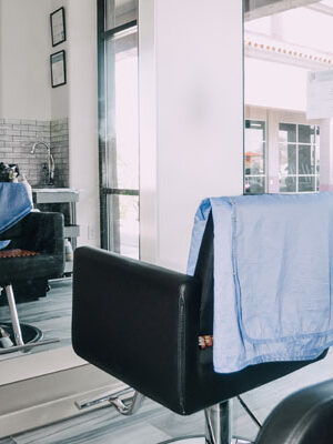 A black salon chair in front of a mirror